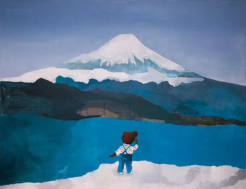 A small figure facing a snow-covered mountain across blue water